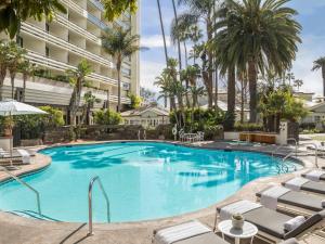 a large swimming pool with chairs and a building at Fairmont Miramar Hotel & Bungalows in Los Angeles