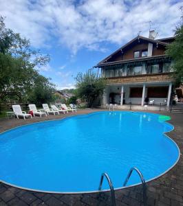 a large blue swimming pool in front of a building at Albergo Garni Villa Lory in Baselga di Pinè