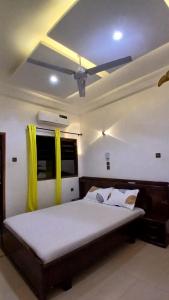 a bedroom with a large bed with yellow curtains at Villa de 3 chambres avec jaccuzzi in Porto-Novo