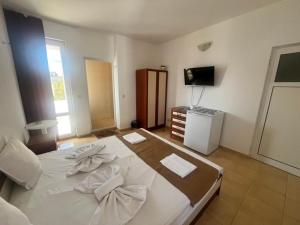 a large white bed in a room with a television at Хотел CANAVAN'S - beach in 2 minutes, free parking and WiFi in Ravda