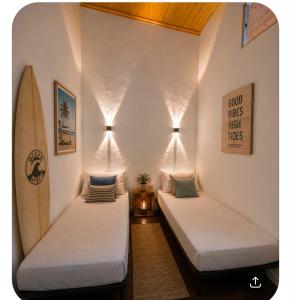two beds in a room with a surfboard at Ria Surf & Stay in Faro