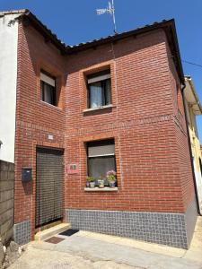 a brick building with two windows and two potted plants at Casa villada in Villada