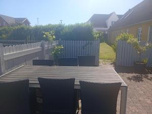 a wooden table and chairs in a backyard with a fence at Vesterhavet in Nørre Vorupør +2 photos