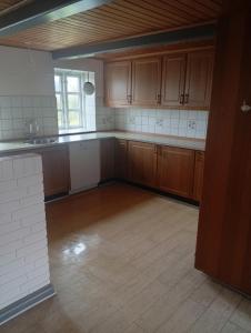 an empty kitchen with wooden cabinets and a wooden floor at Vesterhavet in Nørre Vorupør