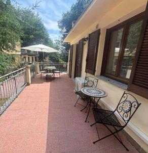 a patio with chairs and tables and an umbrella at Condominio Villa Helios in Cuasso Al Monte