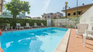 a swimming pool with white chairs and a building at Hotel Kennedy in Lido di Savio