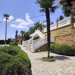 a house with a white staircase and a palm tree at Hacienda Los Manchones in Doña Mencía