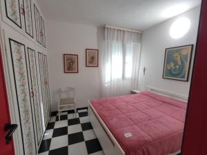 a bedroom with a pink bed and a checkered floor at FronteMare in Lido di Pomposa