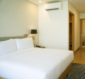 a bedroom with a large white bed and a lamp at Laura Camp side Udawalawe in Udawalawe