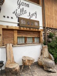 two chairs and a sign on the side of a building at Albergo Garni Villa Lory in Baselga di Pinè