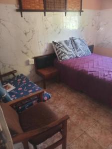 a bedroom with a purple bed and a chair at Sleep Well in Amanzimtoti