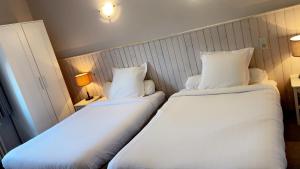 two beds in a hotel room with white pillows at Au Bon Accueil in Alban