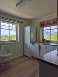a kitchen with a refrigerator and a sink and two windows at Apartment on Leknes with a view in Vestvågøya