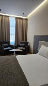 a hotel room with a bed and two chairs at The Center 104 in Polisi i Vogël