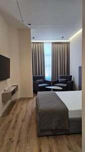 a hotel room with a bed and chairs and a television at The Center 104 in Polisi i Vogël