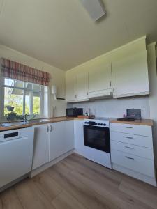 a white kitchen with white cabinets and a window at Apartment on Leknes with a view in Vestvågøya +32 photos