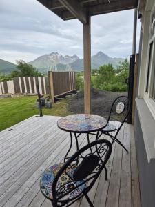 a table and chairs on a wooden deck with mountains at Apartment on Leknes with a view in Vestvågøya