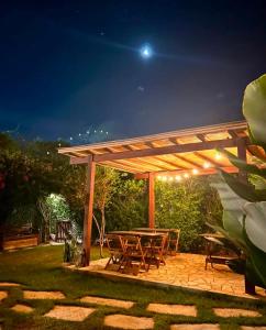 a wooden pergola with a picnic table in a yard at night at Hospedaria Oitis in Búzios +15 photos
