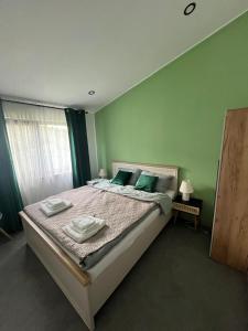 a bedroom with a large bed with green walls at Chalet 1602 in Avrig