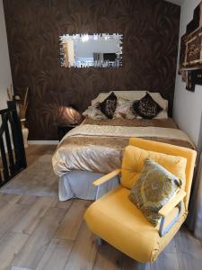 a bedroom with a bed with a yellow chair and a mirror at La Terrasse Salon de The in Montmorillon