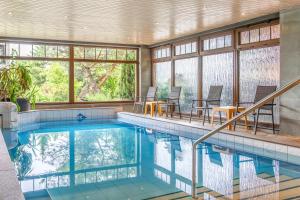 an indoor pool with tables and chairs and windows at Schlossberghotel Oberhof in Oberhof