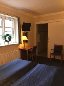 a bedroom with a bed and a desk and a window at Reersø Kro in Reersø
