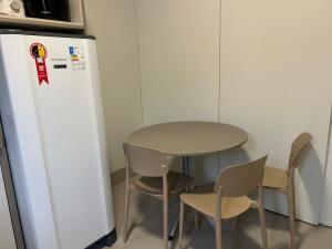 a table and chairs next to a table and a refrigerator at J&C 04 Studio in Primavera do Leste