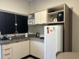 a kitchen with white cabinets and a white refrigerator at J&C 04 Studio in Primavera do Leste