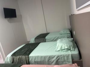 two beds in a small room with a tv at J&C 04 Studio in Primavera do Leste