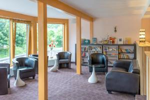 a waiting room with chairs and a table and a book shelf at Schlossberghotel Oberhof in Oberhof