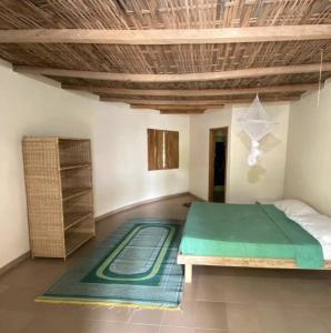 a bedroom with a large bed and a rug at Campement solidaire Nioko Bokk in Abémé +48 photos