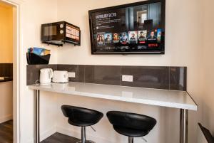 a bar with two stools and a tv on the wall at Cushendall Coastal Accommodation, Glens of Antrim - Beach & Mountain Access in Cushendall