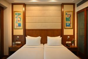 a bedroom with a bed with two white pillows at Savoy Suites Greater Noida in Greater Noida +42 photos