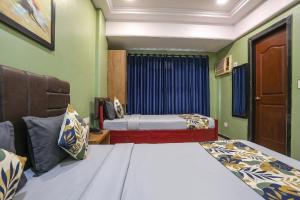 two beds in a room with green walls at FabHotel Maple Leaf in Hyderabad