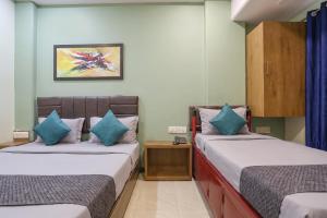 two beds in a room with blue pillows at FabHotel Maple Leaf in Hyderabad