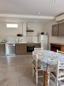 a kitchen with a table with chairs and a refrigerator at Maison classée 3 étoiles avec garage et 2 terrasses in Arles-sur-Tech +3 photos