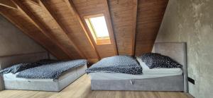 two beds in a attic bedroom with a window at Alpine Chalet Krkonose in Prosečné