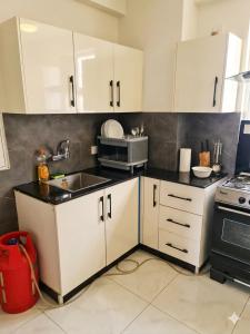 a kitchen with white cabinets and a sink at Zameen Opal Executive 2-Bed Suite in Lahore