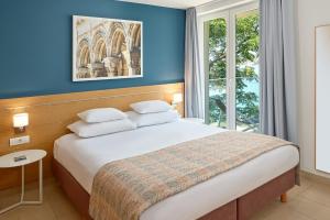 a bedroom with a bed with blue walls and a window at Maistra Select Mlini Villas and Apartments in Mlini