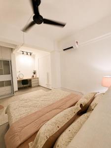a large bed in a white room with a ceiling fan at The Teduh Homestay By Rumah Mimpi in Kertih