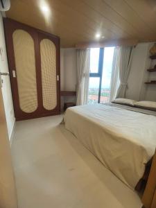 a bedroom with a large bed and a large window at Sunora Stay A6 in Quang Ãm