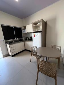 a kitchen with a table and chairs and a refrigerator at Estúdio J&C 05 A in Primavera do Leste