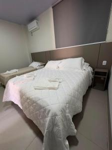 a bedroom with a large bed with a white comforter at Estúdio J&C 05 A in Primavera do Leste