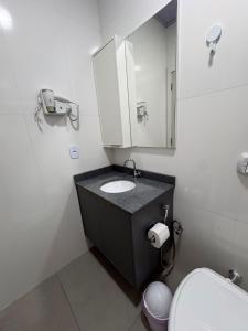 a bathroom with a sink and a mirror and a toilet at Estúdio J&C 05 A in Primavera do Leste
