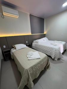 a hotel room with two beds with towels on them at Estúdio J&C 05 A in Primavera do Leste
