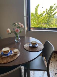 a wooden table with two cups and a vase with flowers at Sotto la Torre - dimora elegante con vista sulla valle in Caiazzo