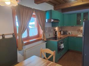 a kitchen with green cabinets and a wooden table at Drevenica pod Lánom in Zuberec