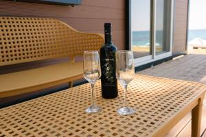 a bottle of wine sitting on a table with two wine glasses at Burano Camping Beach-Bar in Néa Thésis