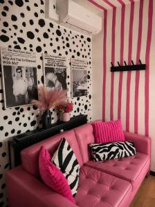 a pink couch in a room with a striped wall at Studio Superstar in Forbach