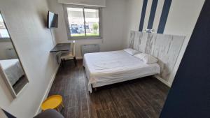 a small room with a bed and a window at Hotel Le Rohu Vannes in Séné